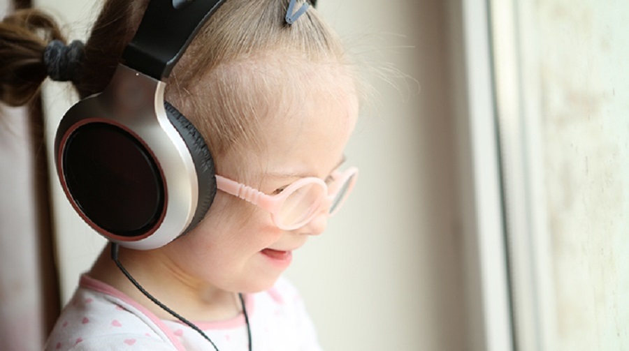 beautiful girl with Down syndrome is listening to music on headp